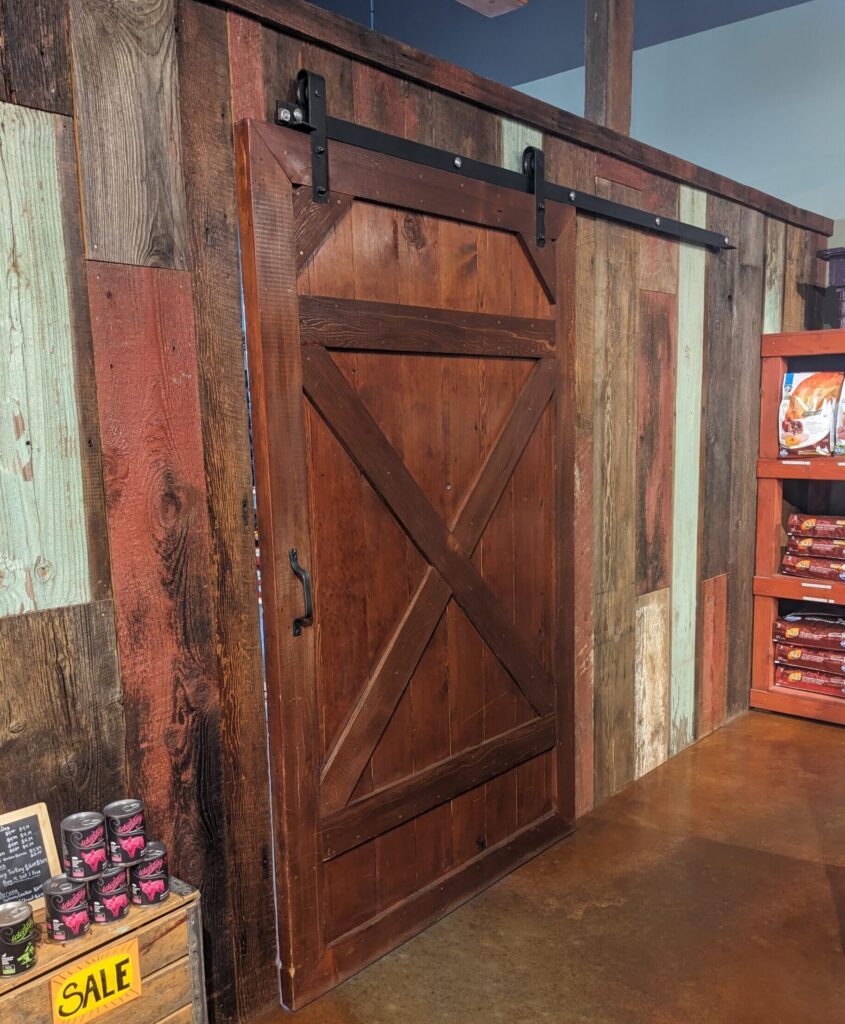 A sliding style barn door hangs against a wall of mis-matched wooden panels.