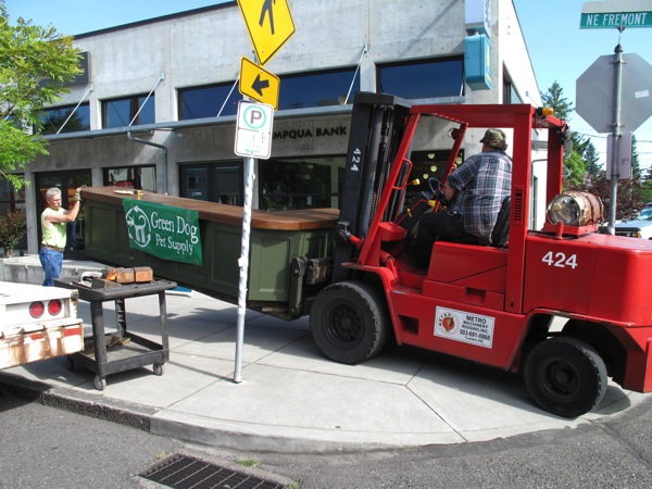 A big red fork lift carries the front counter down the sidewalk to the new store location